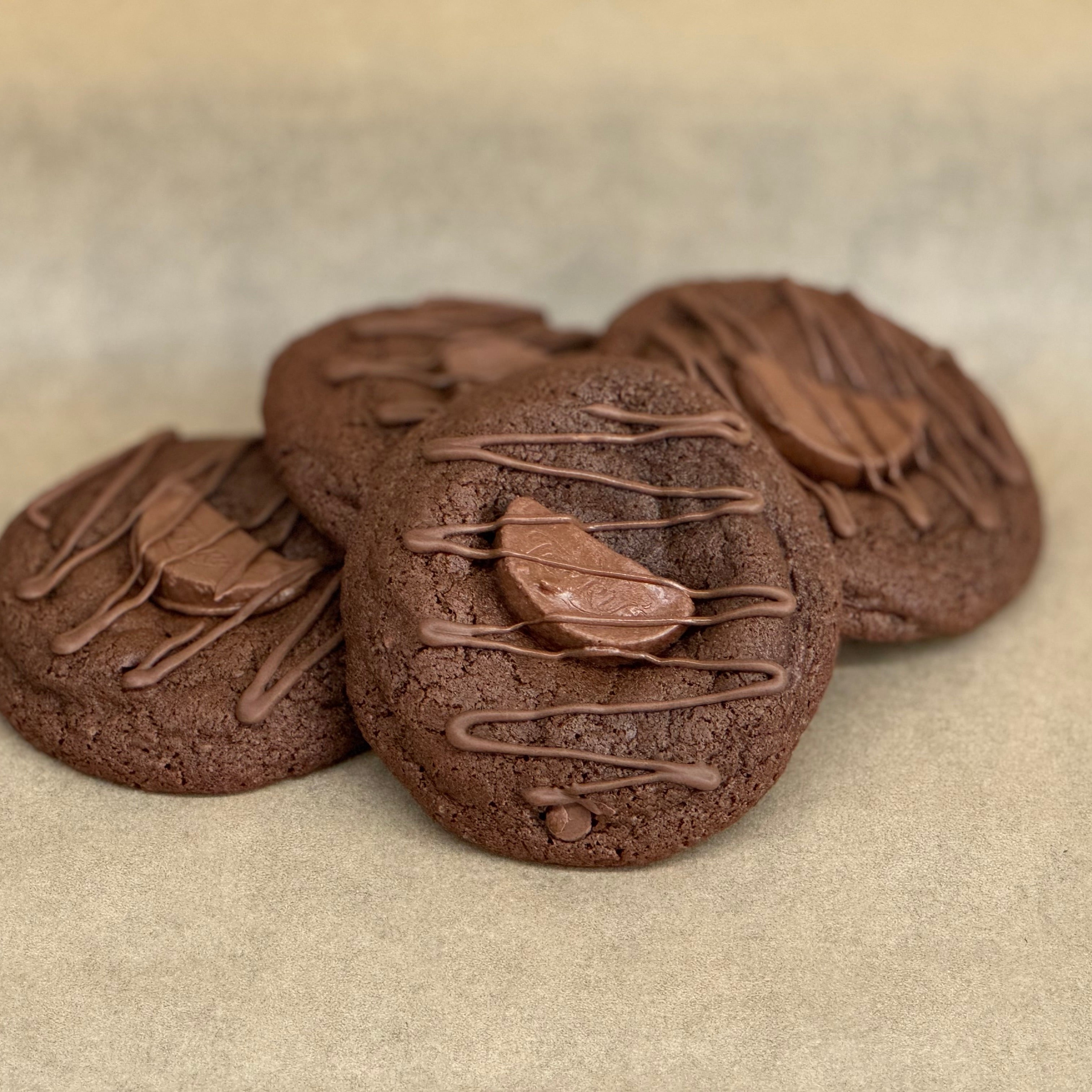 Chocolate cookies with drizzle on a beige surface