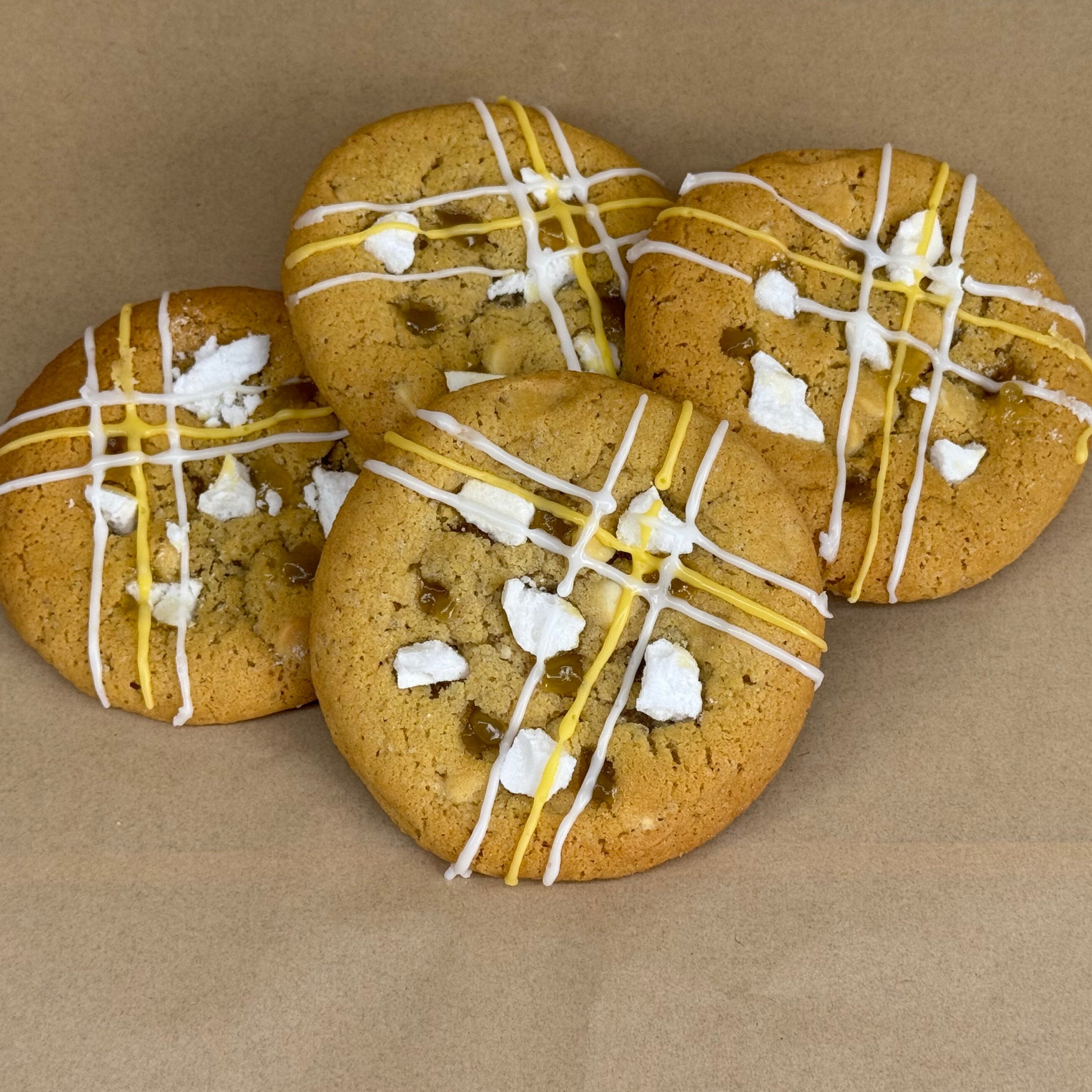 Cookies with white and yellow drizzle with meringue pieces on top