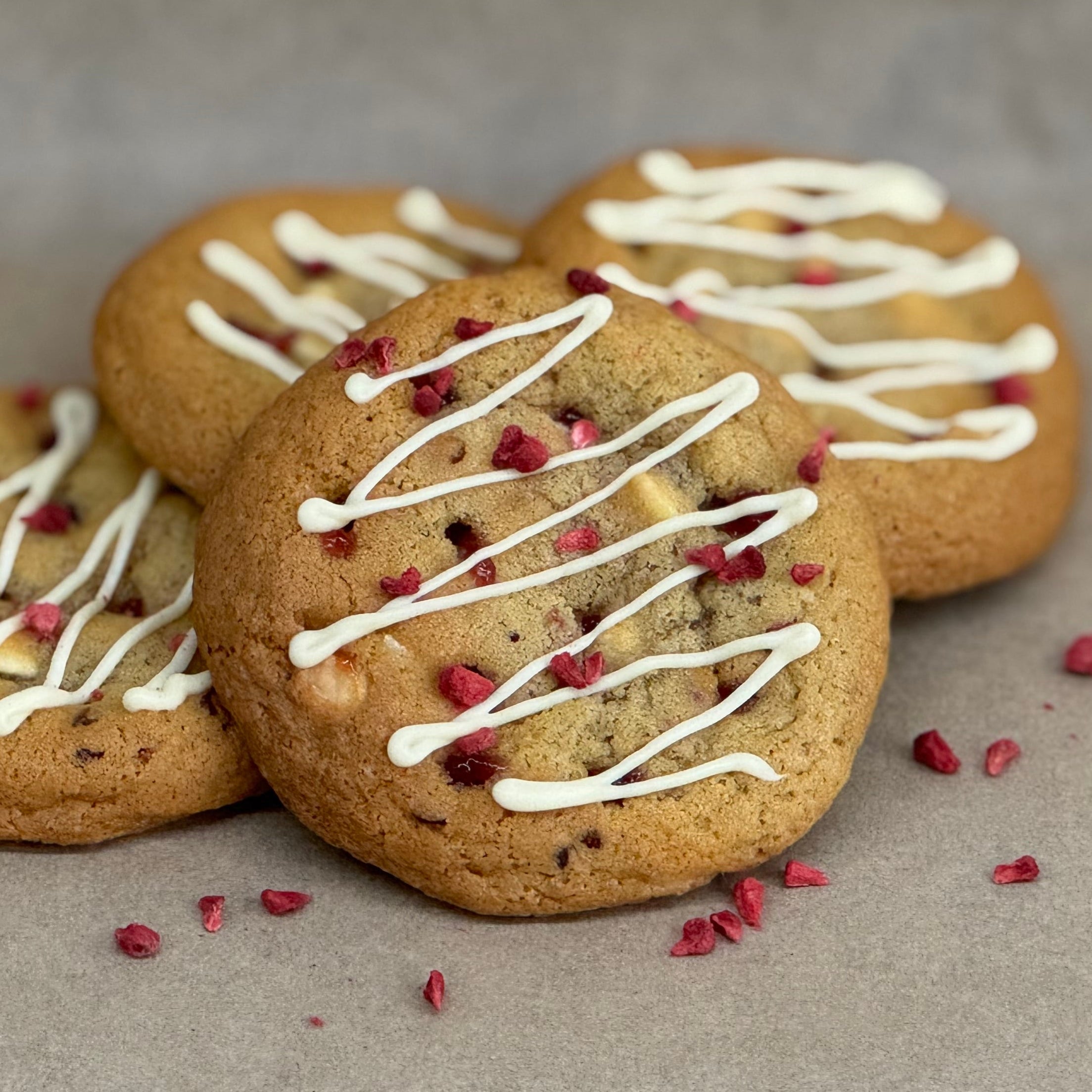 Raspberry & white chocolate gooey cookies with white chocolate drizzle and freeze dried raspberries on top.