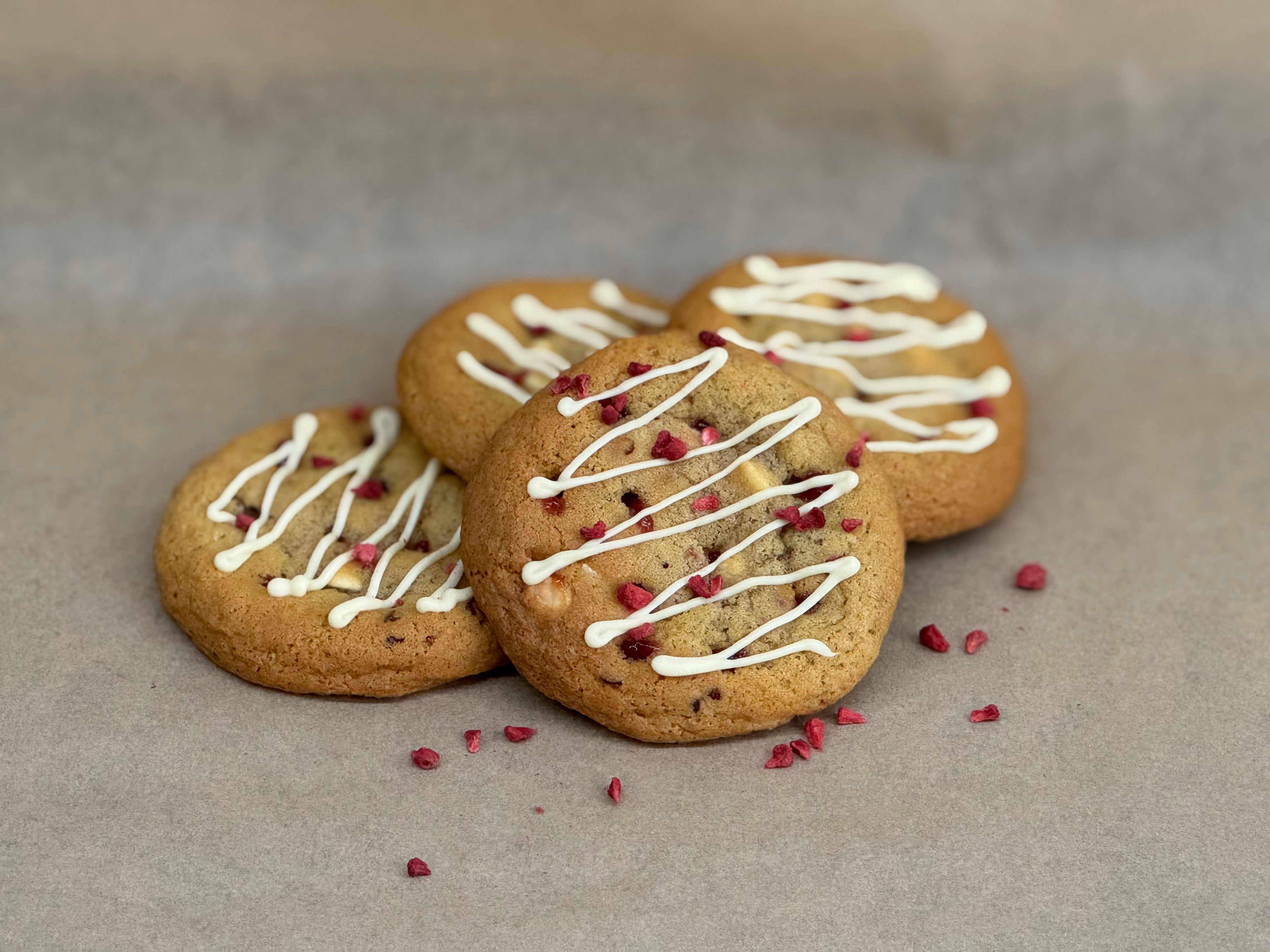 Raspberry & white chocolate gooey cookies with white chocolate drizzle and freeze dried raspberries on top.
